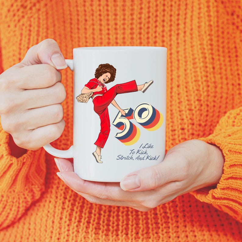May include: White ceramic mug with a cartoon illustration of a woman kicking a large number 50. The text "I Like To Kick, Stretch, And Kick!" is printed below the illustration.