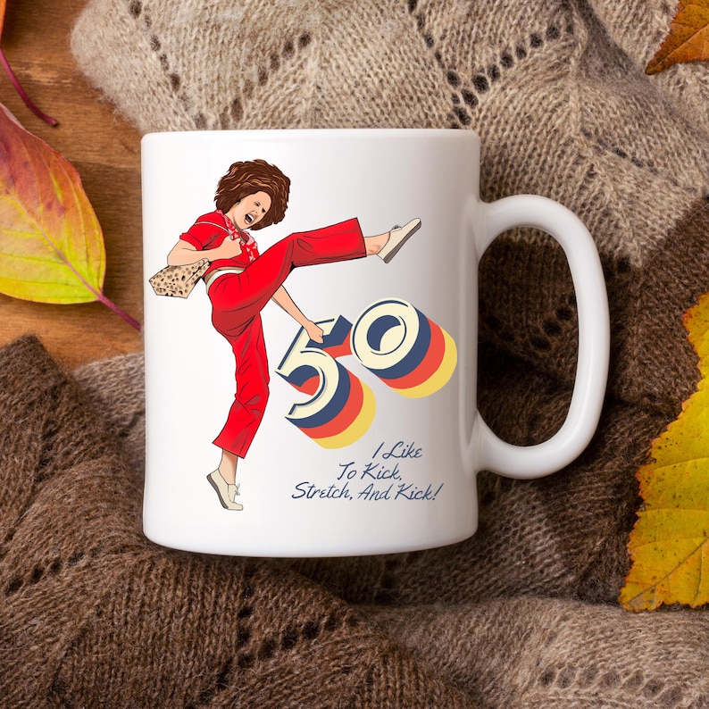 May include: White ceramic mug with a colorful illustration of a woman kicking a large number 50. The text "I Like To Kick, Stretch, And Kick!" is printed below the illustration.
