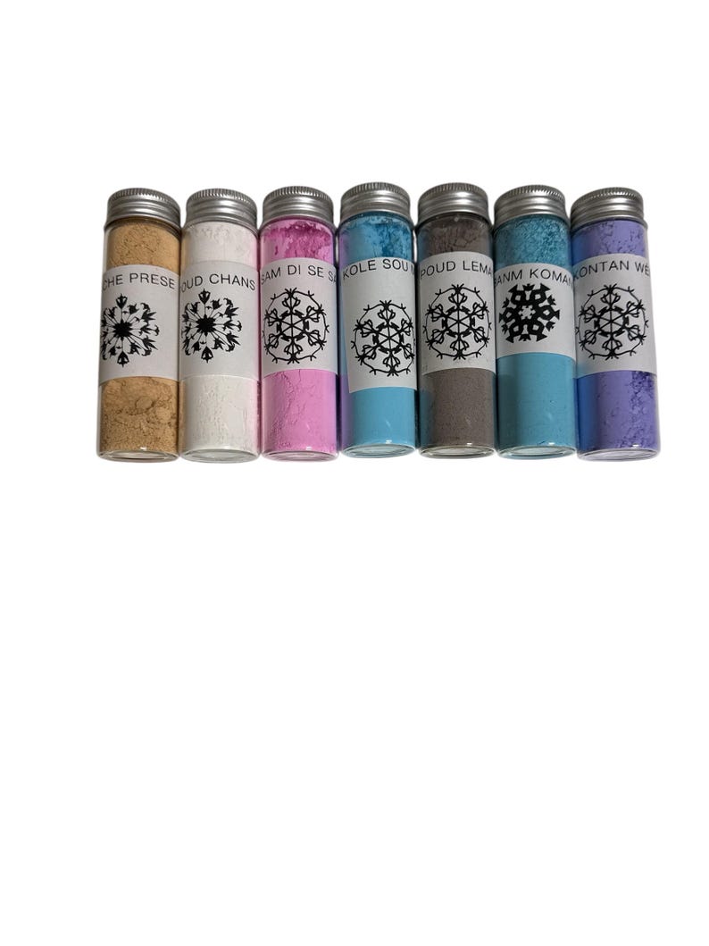 May include: Seven small glass bottles with silver lids, each filled with a different colored powder. The colors include tan, white, pink, light blue, gray, teal, and lavender. Each bottle has a white label with a snowflake design and text.