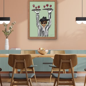 May include: A framed art print depicts a person in a black and white striped suit and hat, holding two trays of wine glasses. The artwork is set against a light green background. The room has a wooden table and chairs.