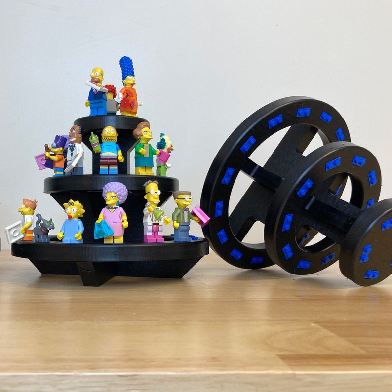 May include: A black and blue spinning toy with a multi-level display stand featuring a collection of yellow, blue, and red Lego minifigures.