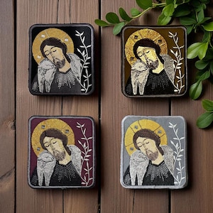 Op de afbeelding: Vier geborduurde patches met een religieus icoon, elk met een gouden halo, die een figuur met een lam afbeelden. De patches hebben zwarte, bruine, bordeauxrode en grijze achtergronden. Witte bloemenborduurwerk.