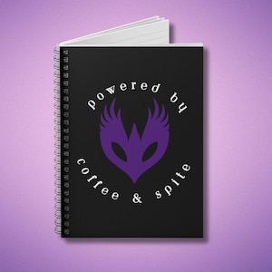 May include: Black spiral notebook with a purple graphic and the text "powered by coffee & spite".