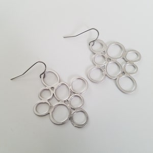 May include: A pair of silver earrings with a geometric design of interlocking circles.