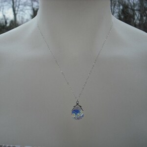 Puede incluir: Un collar de cadena de plata con un colgante de cristal iridiscente.