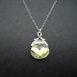 Puede incluir: Un collar de cadena de plata con un colgante en forma de l&aacute;grima con un cristal verde claro facetado.