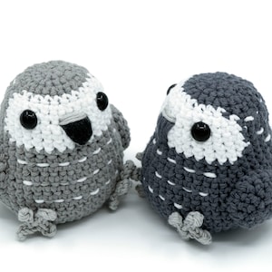 May include: Two crocheted grey and white bird plushies with black eyes. One bird has a red tail feather.