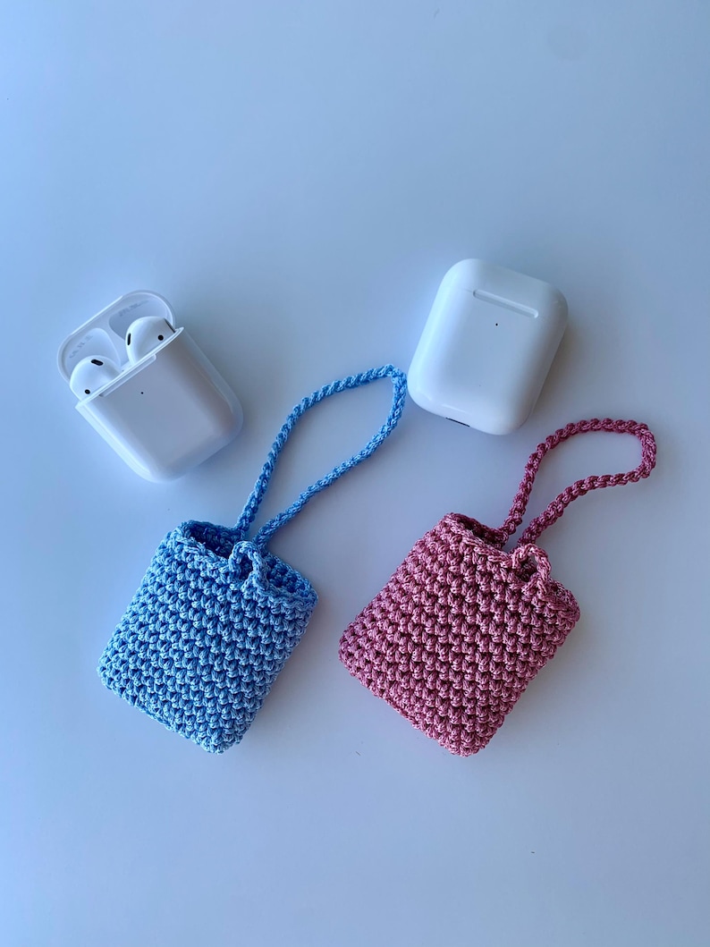 May include: A light blue and a pink crochet case for wireless earbuds, each with a matching strap. Two white earbud cases are also in the image. The cases are handmade and likely designed to protect the earbuds.