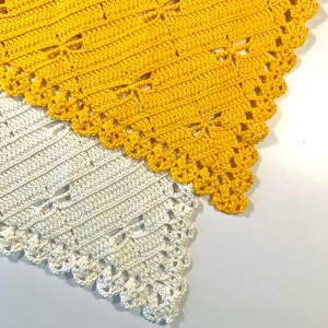 K&ouml;nnte beinhalten: Zwei handgefertigte H&auml;kelschal. Einer ist leuchtend gelb, der andere cremefarben. Beide haben ein Libellenmuster und einen gewellten Rand. Die Schals sind aus weichem Garn gefertigt und eignen sich perfekt, um jedem Outfit einen Hauch von handgefertigtem Charme zu verleihen.