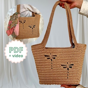 May include: A crocheted tote bag in a warm brown hue, featuring dragonfly cutouts. The bag has long handles and a rectangular shape. A smaller, similar bag is shown in the background, along with a scarf. The text "PDF + video" is in a green and white circle.