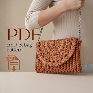 Puede incluir: Un bolso tejido a ganchillo de color marrón cálido, con una solapa decorativa y una correa de cadena plateada. La solapa tiene un patrón circular. El texto "PDF crochet bag pattern" está en la imagen.