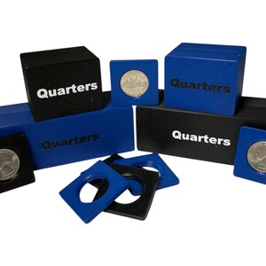 May include: A selection of coin holders and storage boxes, labelled "Quarters." The holders are blue and black, with a square design to hold the coins. The boxes are also blue and black, with the word "Quarters" printed on them.