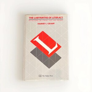 May include: A book titled "The Labyrinths of Literacy" with the author Harvey J. Graff. The cover features a red and white geometric design with the letter "L" and a gray shape on a light gray background with a diamond pattern.
