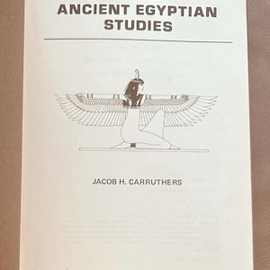 May include: Book cover with the title "Essays in Ancient Egyptian Studies" by Jacob H. Carruthers. The cover features a black and white illustration of a winged goddess kneeling with her arms outstretched.