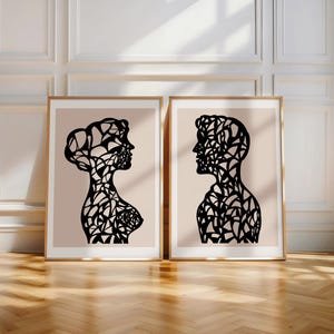 Könnte beinhalten: Zwei Schwarz-Weiß-Silhouetten-Drucke eines Männer- und Frauenprofils auf einem hellrosa Hintergrund. Die Silhouetten bestehen aus komplizierten geometrischen Mustern.
