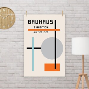 Puede incluir: Un póster minimalista con el texto "Bauhaus Exhibition July 23, 1923" y formas geométricas en negro, naranja, azul claro y gris.