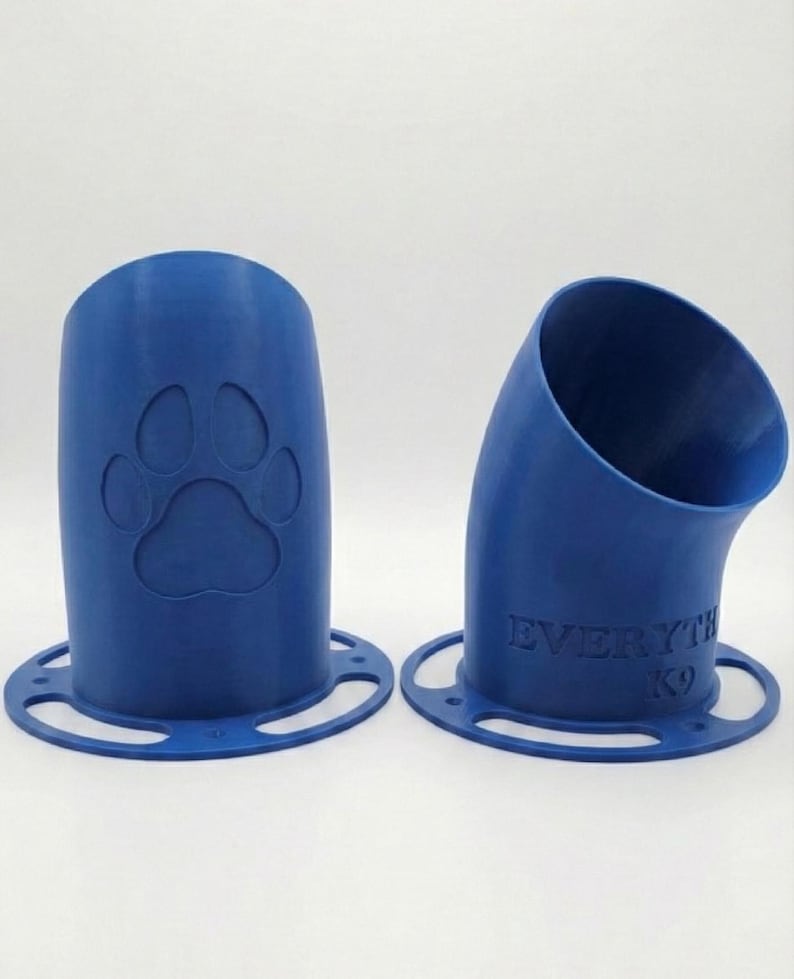 K&ouml;nnte beinhalten: Zwei blaue, 3D-gedruckte Hundeleckerli-Spender. Einer ist zylindrisch mit einem Pfotenabdruck, der andere ist gebogen mit dem Text "EVERYTHING K9". Beide haben eine kreisf&ouml;rmige Basis mit L&ouml;chern.