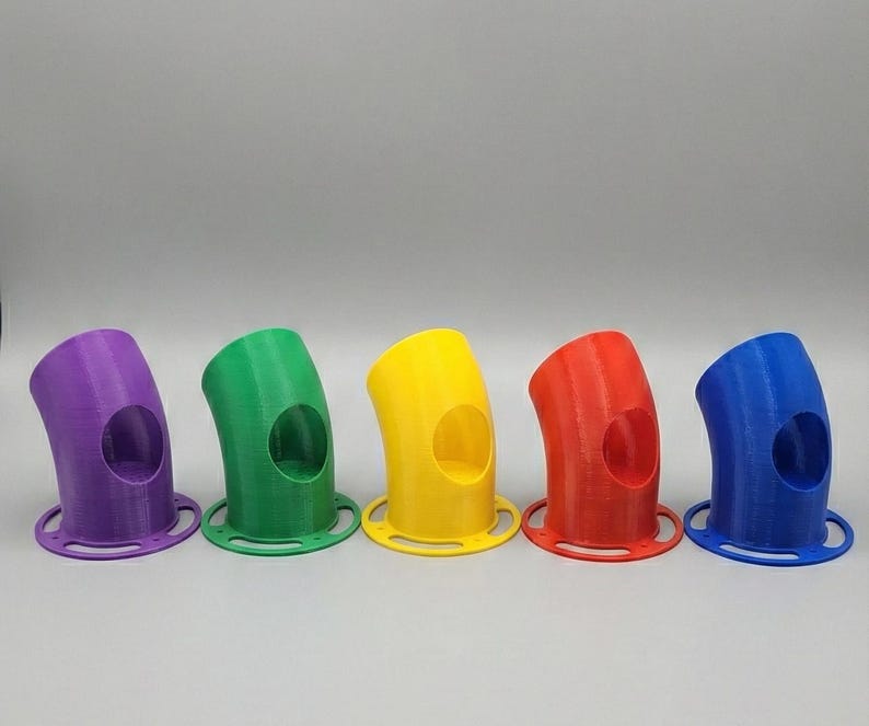 K&ouml;nnte beinhalten: F&uuml;nf bunte, gebogene Vogelfutterspender aus Kunststoff in Lila, Gr&uuml;n, Gelb, Rot und Blau. Jeder Futterspender hat eine kreisf&ouml;rmige &Ouml;ffnung und einen kreisf&ouml;rmigen Sockel. Die Futterspender sind in einer Reihe vor neutralem Hintergrund angeordnet.