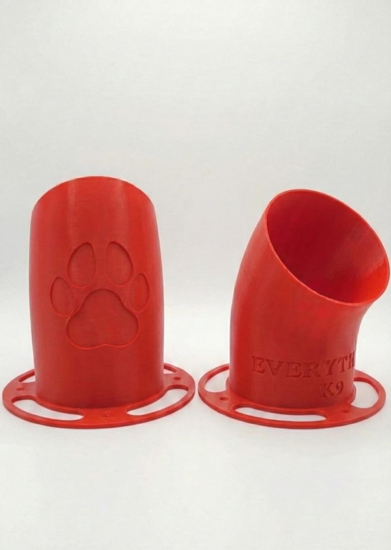 K&ouml;nnte beinhalten: Zwei rote, 3D-gedruckte Hundeleckerli-Spender. Einer hat einen Pfotenabdruck, der andere den Text "EVERYTHING K9". Beide haben eine kreisf&ouml;rmige Basis mit L&ouml;chern. Die Spender sind zylindrisch mit einer gebogenen &Ouml;ffnung.