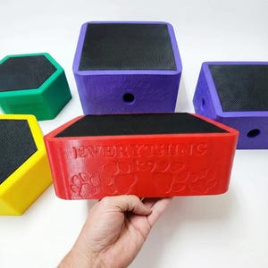 May include: A selection of brightly coloured pet steps. The steps are in red, purple, green, and yellow. Each step has a black, textured top surface. The red step has the text "EVERYTHING DOGS" with paw prints.