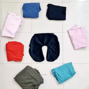 May include: A collection of folded fabric in various colours, including pink, blue, red, green, and black. A dark blue travel neck pillow is also included.