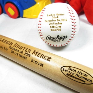 May include: A wooden baseball bat engraved with "Larkin Hunter Merck" and birth details: December 26, 2016, 8 lbs 2 oz, 20 1/2 inches, 9:32 PM. The bat also has a circular engraving that says "Our New Little Slugger".