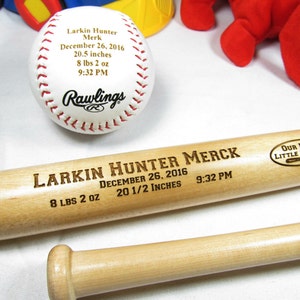 May include: Personalized baseball bat and ball set with the name Larkin Hunter Merck, birth date December 26, 2016, weight 8 lbs 2 oz, and height 20 1/2 inches. The bat is engraved with "Our New Little Slugger".