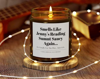 Puede incluir: Una vela de vidrio marrón con una etiqueta blanca que dice "Smells Like Jenny's Reading Sumnt Saucy Again... It's Totally For The Plot... Sure it is. CANDLE HERITAGE ECO FRIENDLY".