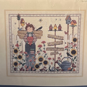 Könnte beinhalten: Stickmuster-Set mit einer skurrilen Illustration eines Mädchens mit einer Sonnenblume und einem Schild mit der Aufschrift "Willkommen Schmetterlinge Marienkäfer und Bienen". Das Set enthält 14er Stoff, Stickgarn, eine Nadel und Anleitungen. Das fertige Stück misst 36 cm x 30 cm.