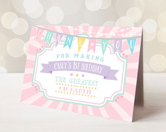 May include: Pink and white thank you card with a circus theme. The card has a banner that says "Thank You" and a sign that says "For Making Casey's 1st Birthday The Greatest On Earth".