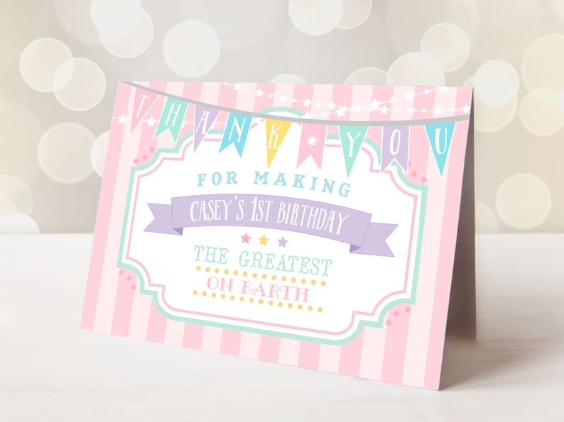 May include: Pink and white thank you card with a circus theme. The card has a banner that says "Thank You" and "For Making Casey's 1st Birthday The Greatest On Earth".