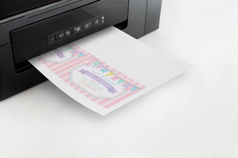 May include: A printer printing out pink and white thank you cards with the text "For making Carly's 1st Birthday The Greatest On Earth!"