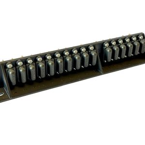May include: A black fuse holder with multiple fuses. The fuses are black with silver tops and are arranged in a row. The holder has mounting holes and is designed for electrical applications.