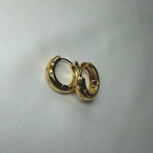 May include: A pair of gold hoop earrings with small clear stones set around the hoops.