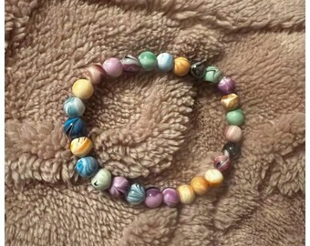 May include: A colorful beaded bracelet with a variety of patterns and colors, including blue, green, purple, and yellow.