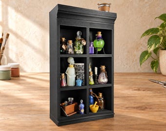 May include: A black wooden display shelf with six compartments containing miniature glass bottles, a small skeleton figurine, a mortar and pestle, and various decorative items. The shelf has a flat top and a rectangular frame structure.