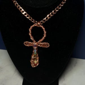 May include: A copper chain necklace with a copper wire wrapped Ankh pendant featuring seven colorful gemstones.