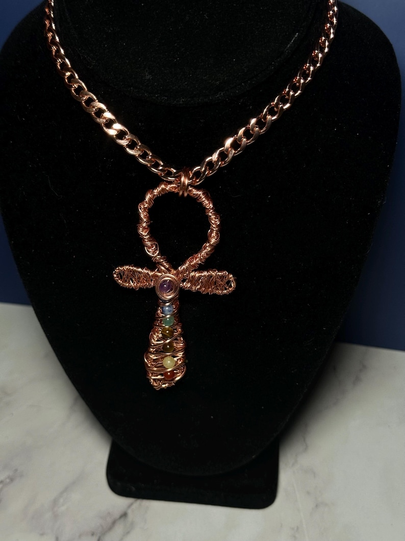 May include: A copper chain necklace with a copper wire wrapped Ankh pendant featuring seven colorful gemstones.