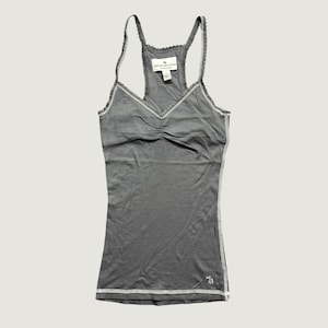 May include: A charcoal grey racerback tank top featuring a V-neckline with delicate lace trim along the edges. The garment includes a small white embroidered logo near the bottom hem and a white interior label reading Abercrombie & Fitch.
