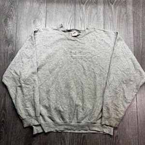 Puede incluir: Una sudadera Nike gris jaspeado con cuello redondo y mangas largas. La palabra "AIR" est&aacute; bordada en el pecho, con un logotipo de Nike swoosh encima y debajo del texto. La sudadera est&aacute; hecha de un material suave y c&oacute;modo.