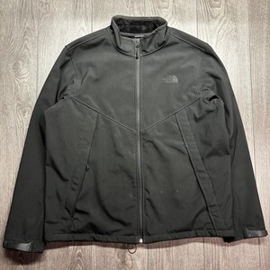 May include: A black jacket with a full-length zip, a high collar, and the North Face logo on the chest. The jacket has a soft, dark lining around the collar and a subtle, textured appearance. The jacket is designed for outdoor activities.