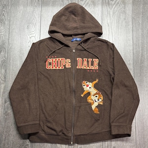 May include: A brown zip-up hoodie with the text "CHIP & DALE" in red and white, and a cartoon graphic of Chip and Dale. The hoodie has a drawstring hood and two front pockets.