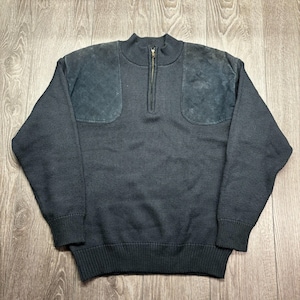 May include: A dark grey sweater with a half-zip and suede shoulder patches. The sweater features a ribbed collar, cuffs, and hem. The fabric has a textured, waffle-knit appearance.