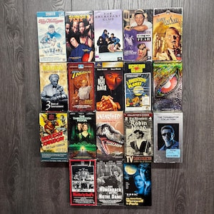 May include: A collection of vintage VHS tapes featuring movie titles like "Charter," "Sunset Park," "The Breakfast Club," and "Cape Fear." The tapes have colorful covers with various actors and movie artwork. The collection includes titles from different genres.