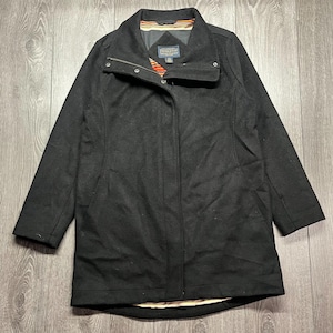 May include: A black wool coat with a stand-up collar and a zip fastening. The coat has a small label and a colourful striped lining visible at the collar. The coat is a mid-length style, suitable for cooler weather.