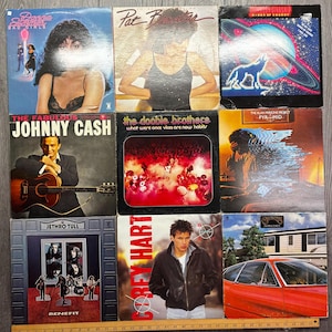 May include: A collection of nine vintage vinyl record albums. The album covers feature various artists, including Donna Summer, Pat Benatar, Johnny Cash, and The Doobie Brothers. The album covers are in various colours and designs.