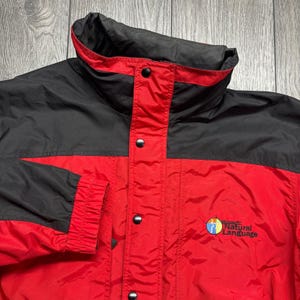 Könnte beinhalten: Rote und schwarze Jacke mit hohem Kragen und Druckknöpfen. Auf der Vorderseite der Jacke steht der Text "Microsoft Natural Language". Die Jacke ist aus einem glänzenden, möglicherweise Nylon-Material gefertigt.