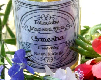 May include: A small glass bottle with a purple label that reads "Fallawake Magickal Arts Ganesha Unblocking Net Wt. 0.50 oz.". The bottle is filled with a clear liquid and contains small, white, dried flowers. The bottle is surrounded by purple, white, and pink flowers.