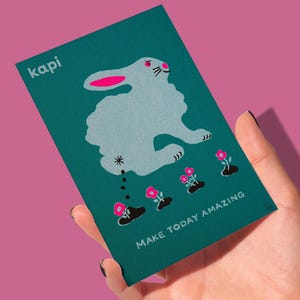 May include: A teal card with a cartoon rabbit illustration and the text "MAKE TODAY AMAZING." The rabbit is light blue with pink accents, and there are pink flowers at the bottom. The word "kapi" is in the upper left corner.