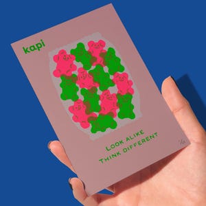 May include: A pink art print featuring a collection of pink and green gummy bear illustrations. The print includes the text "kapi" in green at the top left and "LOOK ALIKE THINK DIFFERENT" in green at the bottom.